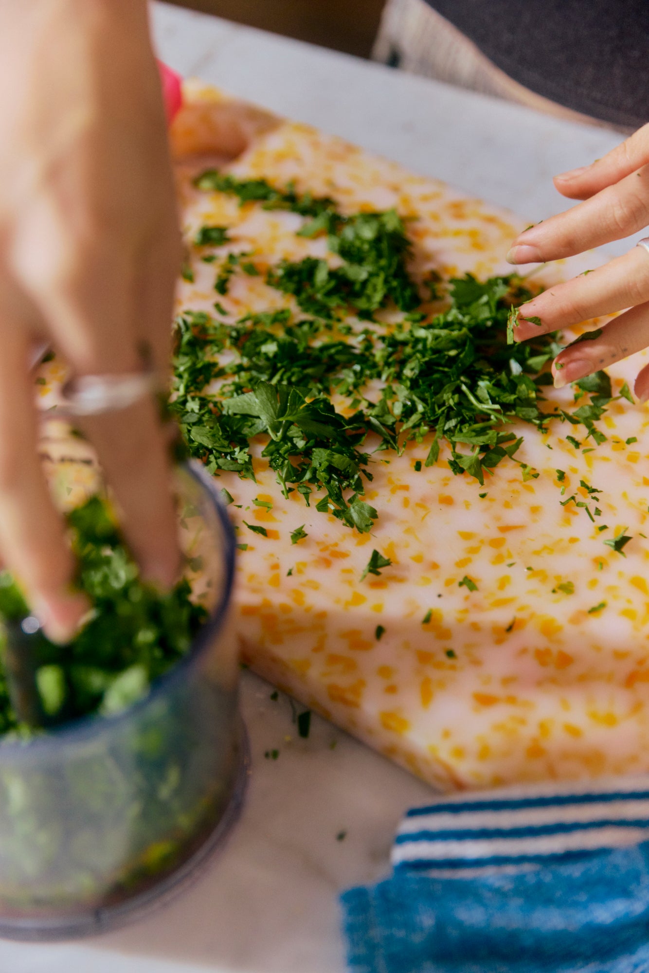 Passionfruit orange CHOPIT chopping board, made from recycled plastics, on a kitchen counter with fresh green herbs and vegetables, perfect for slicing and dicing.